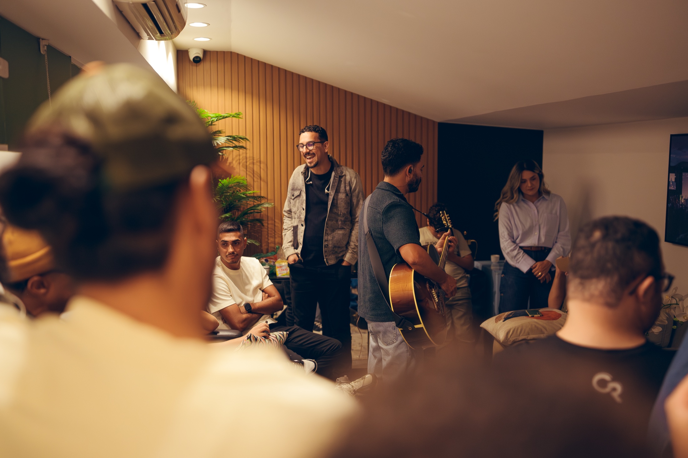Pessoas reunidas informalmente enquanto alguém toca violão.